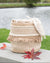 Textured woven basket with a blanket on a wooden surface near a body of water