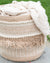Woven basket with a beige and white patterned cover on a blurred green background