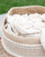 White blanket in a woven basket with a grassy background