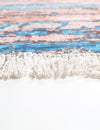 Close-up of a textured rug with a colorful pattern on a white background