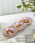 Wooden tray with pink ceramic sections filled with nuts on a light surface.