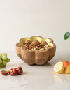 Wooden fruit bowl with assorted nuts and fruits on a light surface