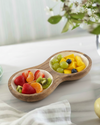 Wooden fruit bowl with compartments filled with fruits on a light surface.