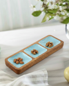 Decorative tray with wooden border and blue sections on a light surface with a pear and flowers in the background.