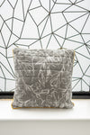 Floral-patterned pillow on a white surface with a geometric black and white wall in the background