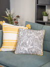 Yellow and gray patterned pillows on a teal couch with a neutral background