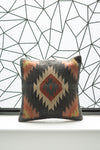 Decorative pillow with geometric pattern against a geometric wall design