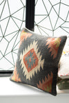 Decorative pillow with geometric pattern on a surface with a geometric wall design in the background