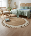 Round woven rug with tassels in a bedroom setting