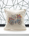 Decorative pillow with bicycle and floral design against a geometric wall.