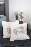 Two decorative pillows with bicycle designs on a chair.