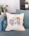 Decorative pillow with bicycle and flowers design on a blue couch