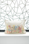 Decorative pillow with floral embroidery against a geometric wall pattern