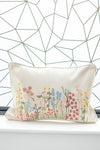 Decorative pillow with floral embroidery against a geometric wall pattern