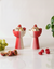 Two red and white ceramic bowls with ice cream and berries on a light surface.