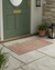 Doormat in front of a green door with stone wall and lanterns.