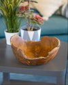 Wooden bowl on a table with potted plants in the background