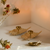 Set of gold decorative items on a white surface with flowers in the background