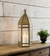 Gold lantern with a candle on a wooden surface against a wooden wall.