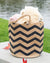 Basket with zigzag pattern filled with beach items by a body of water