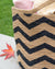 Close-up of a jute bag with black zigzag pattern on a grassy background