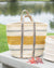 Woven basket with striped pattern on a wooden surface near a body of water