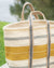 Woven bag with yellow and gray stripes on a blurred natural background
