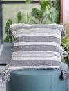 Gray and white striped pillow with tassels on a teal chair outdoors.