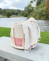 Textile basket with a towel draped over it by a lake