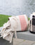Two woven baskets with chevron patterns on a wooden bench by a body of water.