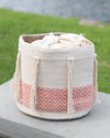 Textile basket with tassels and a chevron pattern on a grassy background