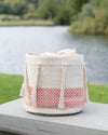 Textile basket with pink and white pattern on a wooden surface by a lake
