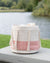 Textile basket with pink and white pattern on a wooden surface by a lake