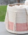 Woven basket with chevron pattern and tassels on a blurred natural background