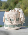 Macrame basket with tassels and geometric patterns on a wooden surface with a blurred natural background