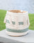 Woven basket with geometric patterns and tassels on a wooden surface with grass and blurred background