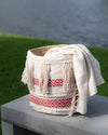 Woven basket with a white blanket draped over it on a wooden surface outdoors.