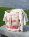 Woven basket with a white blanket draped over it, set against a natural background.