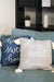 Two pillows with 'home sweet home' text on a couch in a living room setting.