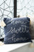 Blue pillow with 'home sweet home' text and tassels on a decorative wall background