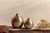 Two gold vases on a wooden surface with a neutral background