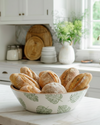 Bowl of bread on a kitchen counter with white cabinets and a window in the background