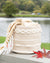 Woven basket with a blanket draped over it by a lake