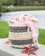 Woven basket with a pink blanket draped over it, set against a natural background with water and greenery.