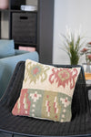 Decorative pillow with geometric pattern on a wicker chair in a living room setting.
