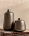 Two metallic vases on a wooden surface with a neutral background