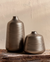 Two metallic vases on a wooden surface with a neutral background