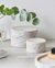 Two marble containers on a light surface with a plant in the background