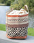 Woven basket with patterned design on a surface near a body of water.