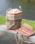 Woven basket with patterned design on a wooden surface near water